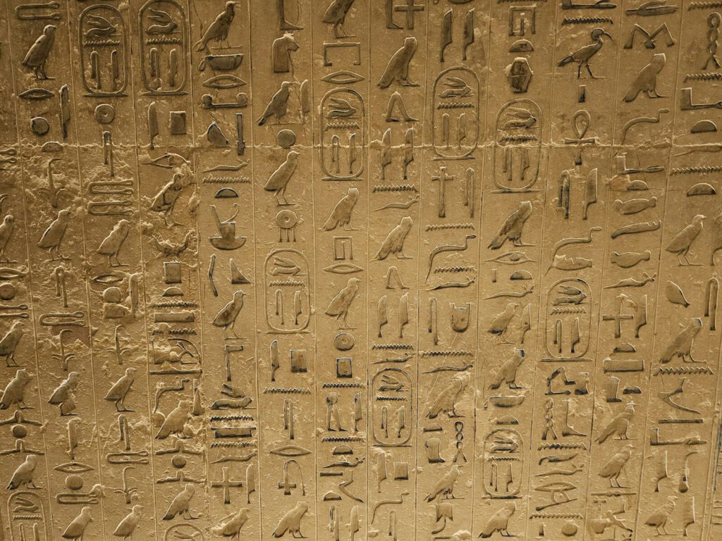 a wall with egyptian writing and birds on it